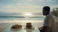 Man choosing between burger and healthy salad by the ocean