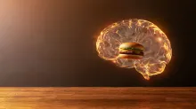 A glowing transparent human brain with a cheeseburger inside, floating above a wooden table, symbolizing how memories of food influence appetite and eating behavior.